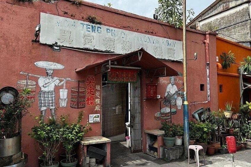 Un edificio con un murale raffigurante una persona che suona le percussioni, piante in vaso e un cartello con caratteri cinesi. 3