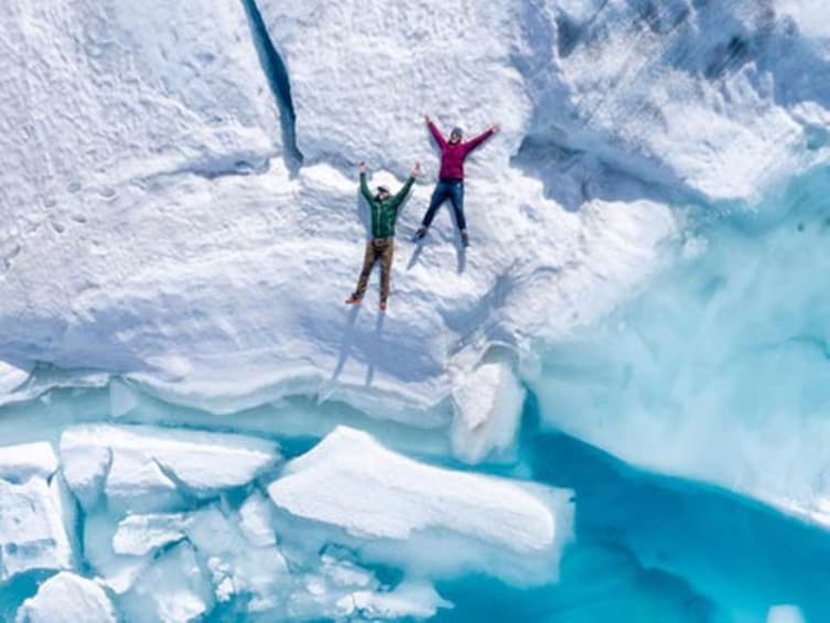 Two people jumping off a cliff into a glacier. 3