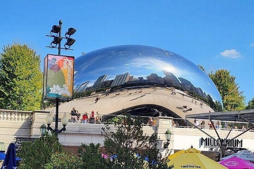 A large reflective dome structure with a cityscape reflection, surrounded by greenery and a clear sky. 4