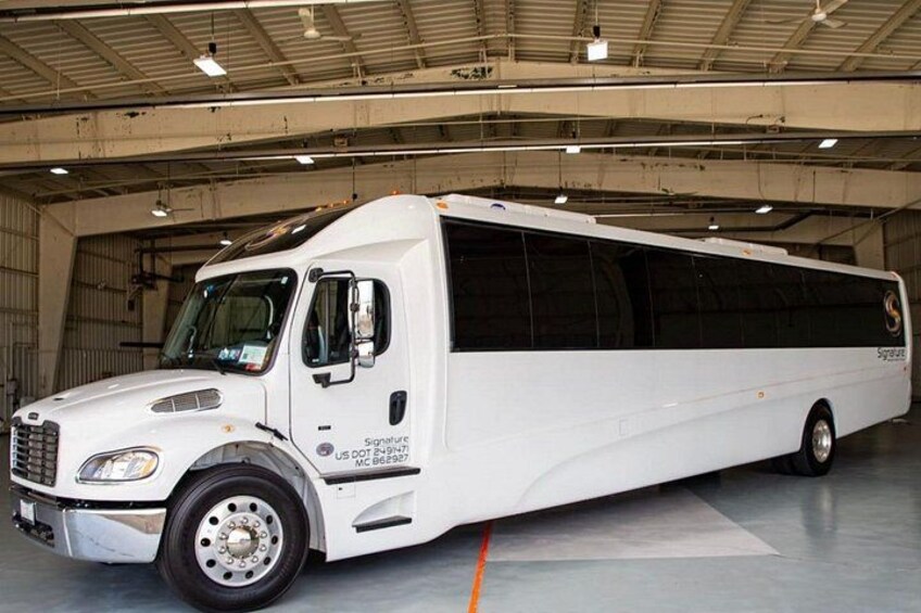 A white transit bus parked inside a hangar. 1