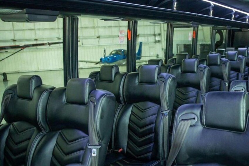 A row of black leather seats with headrests and seat belts, inside a vehicle. 5