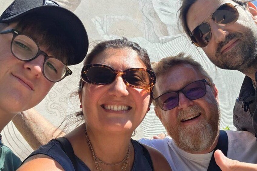 En grupp människor som tar en selfie med en staty i bakgrunden. 2