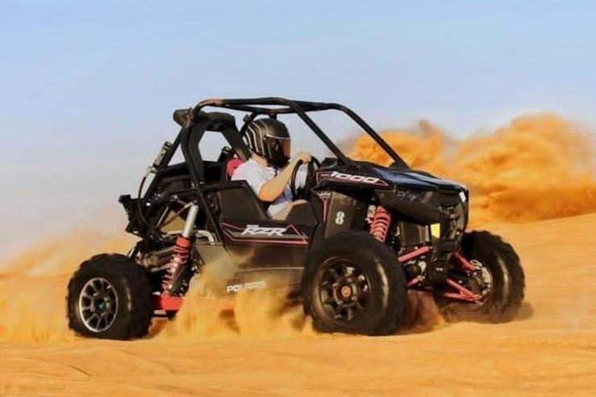 A black off-road vehicle with red and white accents driving through a sandy terrain. 4