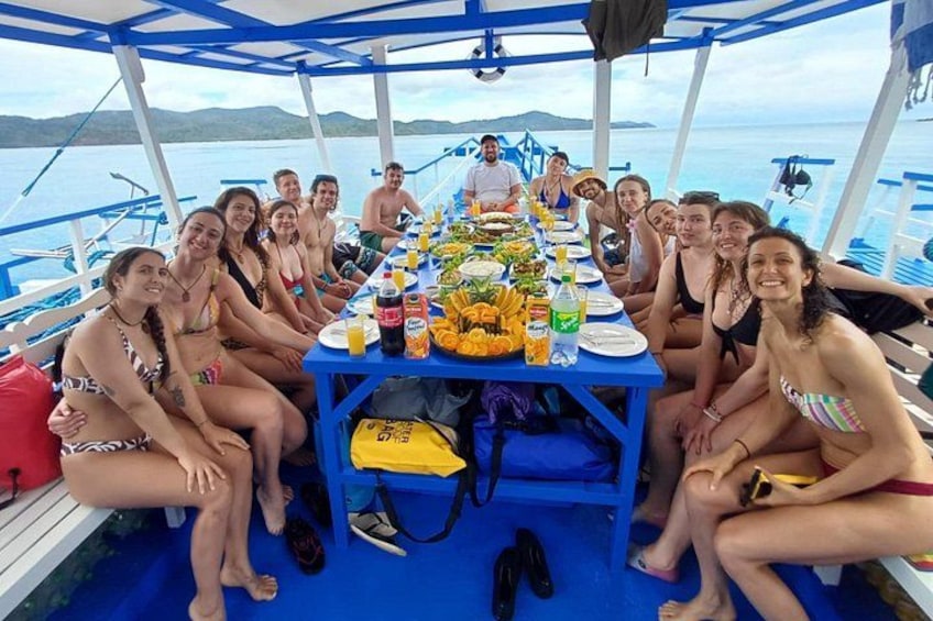 A group of people on a boat with a table set for a meal. 3