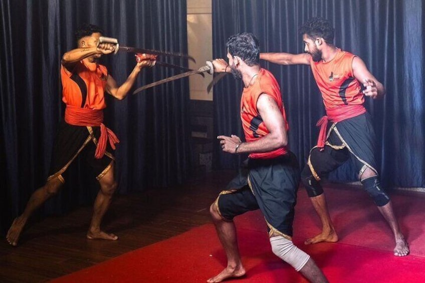Three people in orange and black outfits performing a martial arts demonstration. 5