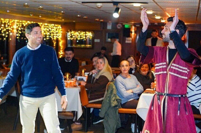 A person in a red jacket performing in a restaurant with tables and chairs. 4