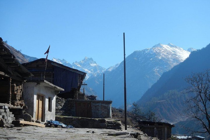 A mountainous village with traditional buildings, a flag, and snow-capped peaks in the background. 3