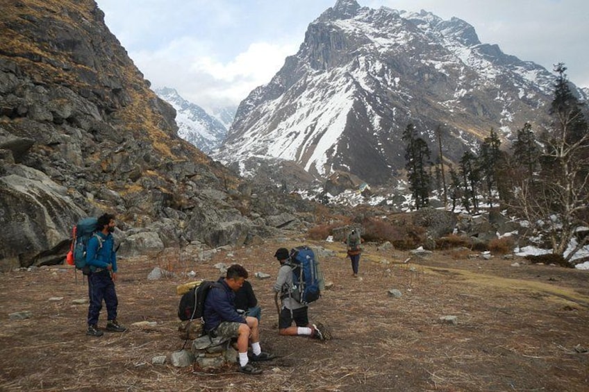A group of hikers in a mountainous area with rocky terrain and snow-capped peaks in the background. 5