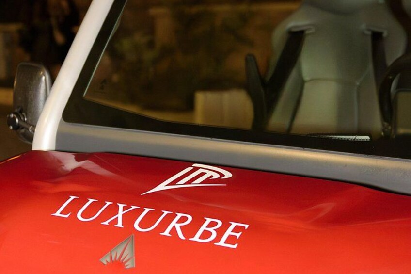 Un'auto rossa con la scritta 'LUXURBE' e un logo sul fianco. 4