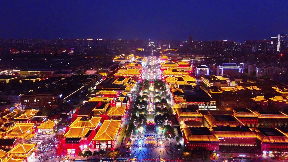 A night view of a traditional market with illuminated buildings and a central tree. 3