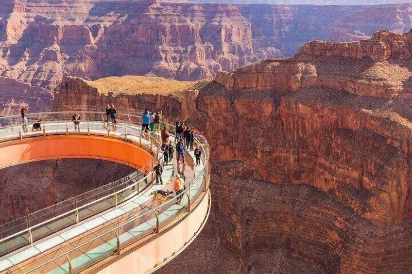 A glass-bottomed bridge with people walking on it, surrounded by canyon cliffs. 2