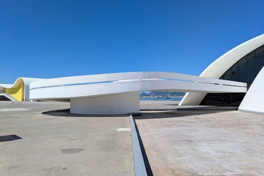 A modern architectural structure with curved white walls and a flat roof. 5