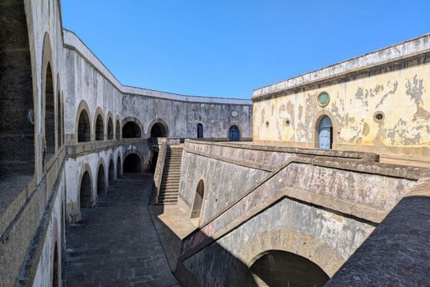 A courtyard with arches, a staircase, and a building with a weathered facade. 2