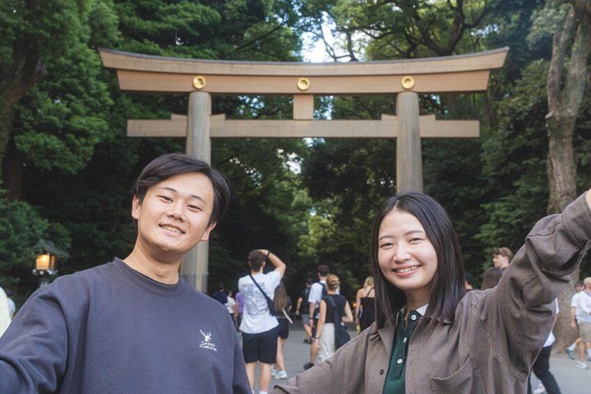 Due persone si fanno un selfie davanti a un tradizionale torii giapponese circondato da alberi. 1