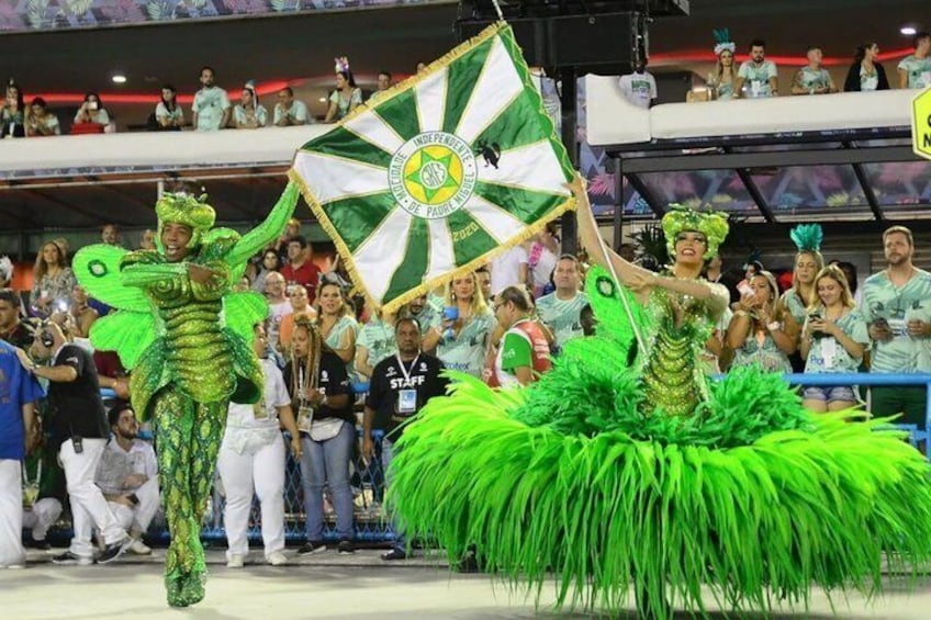 A parade with performers in green costumes and a flag. 2