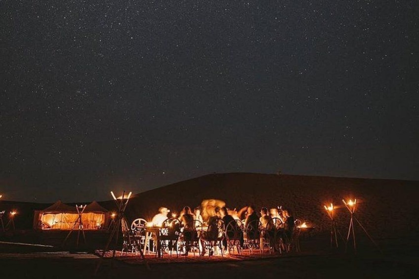 A group of people gathered around a campfire at night under a starry sky. 3