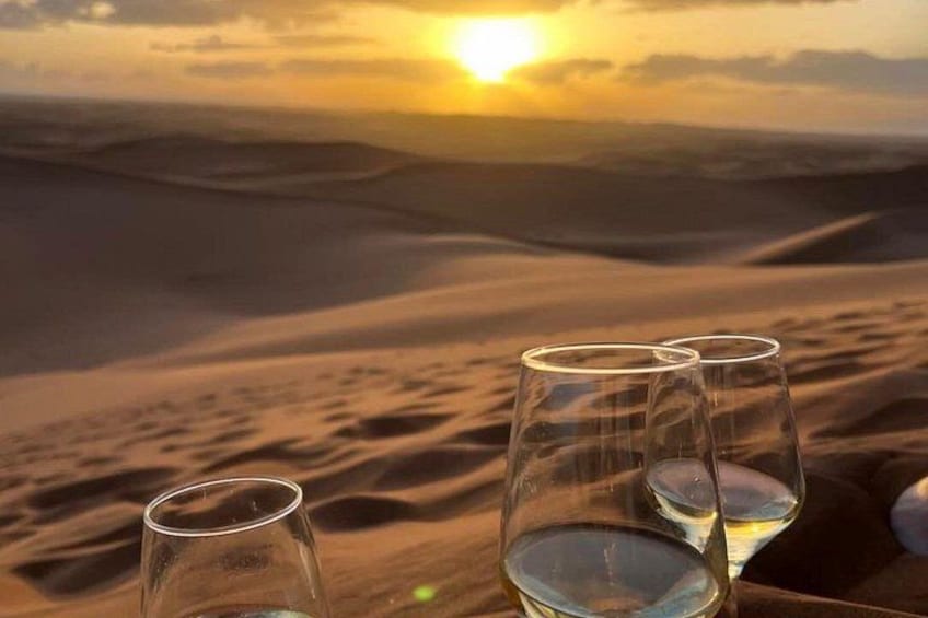 Three glasses of wine on a table with a desert landscape and a sunset in the background. 5