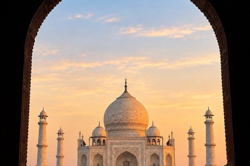 The Taj Mahal with four minarets and a large dome, viewed through an archway. 2