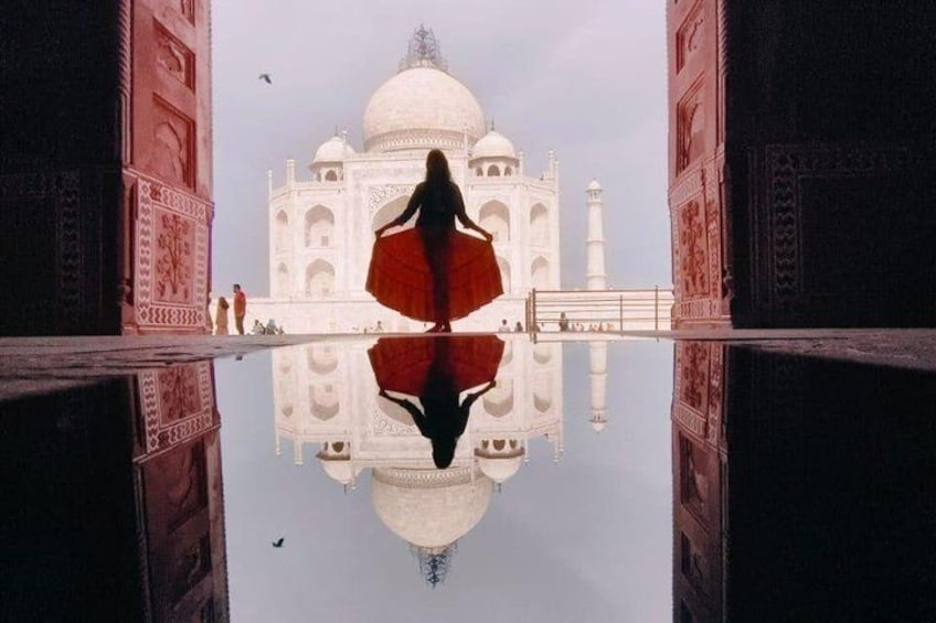 A person standing in front of the Taj Mahal with its reflection in the water. 3