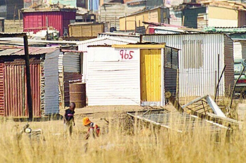Zona rural con edificios de chapa, una persona caminando y un niño jugando. 5