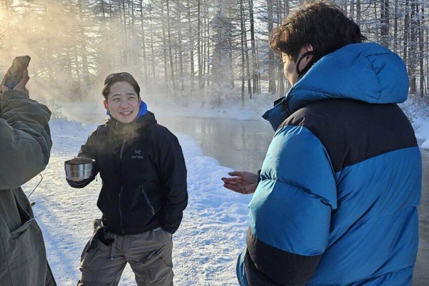 A group of people outdoors in a snowy forest with a river. 3