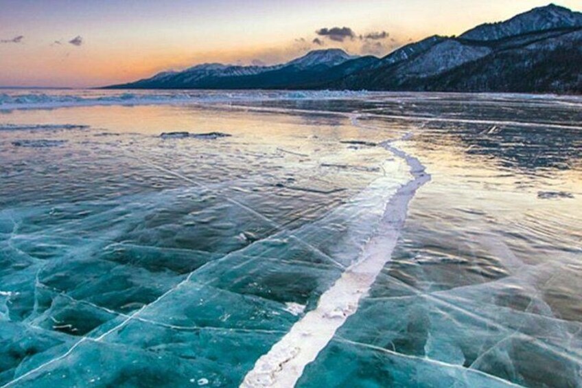 A frozen lake with a clear ice path and mountains in the background. 5