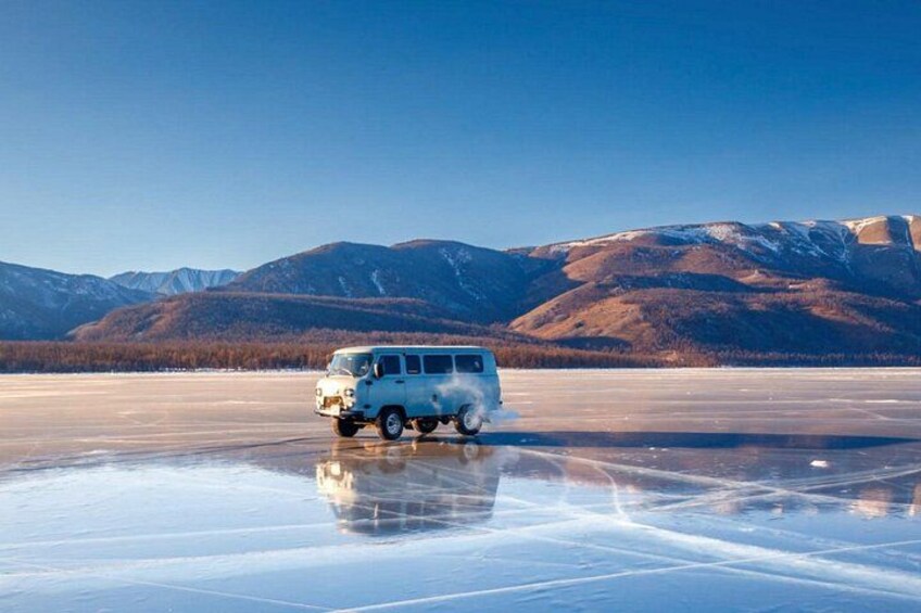 A white van on a frozen lake with mountains in the background. 4