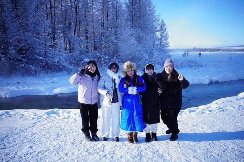 A group of people standing on a snow-covered field with trees in the background. 1