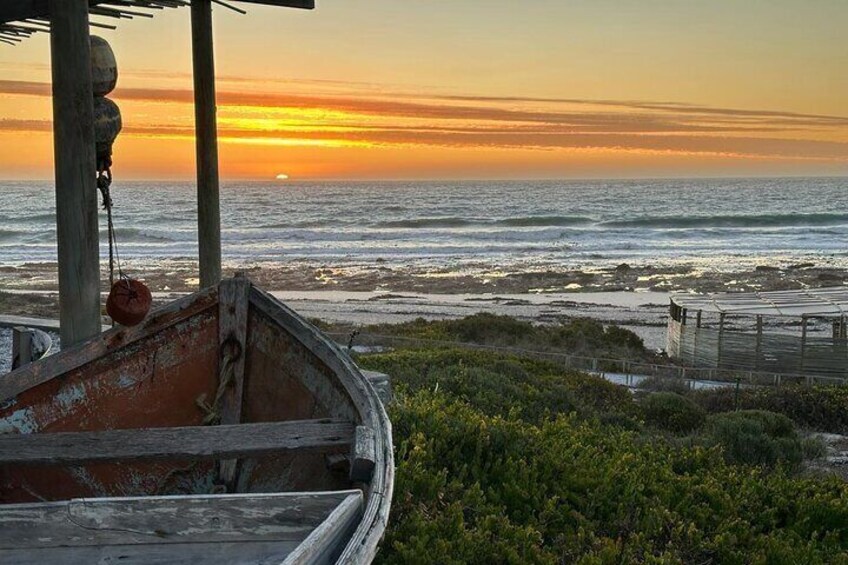 A sunset over the ocean with a boat and a pier in the foreground. 4