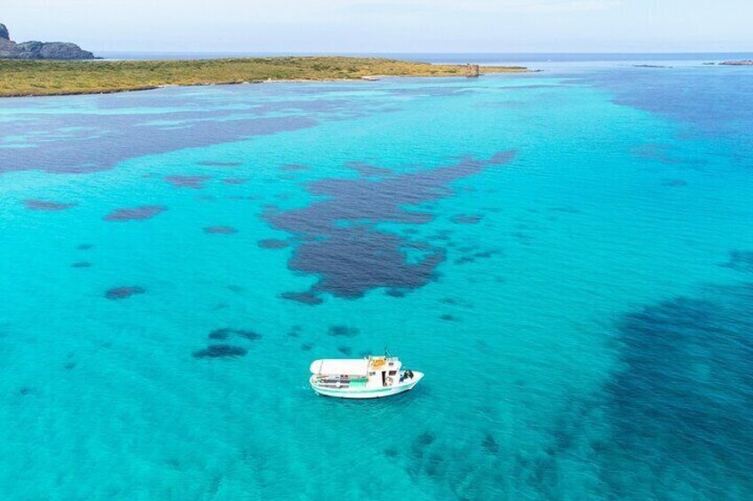 A boat in clear turquoise waters with coral formations. 2