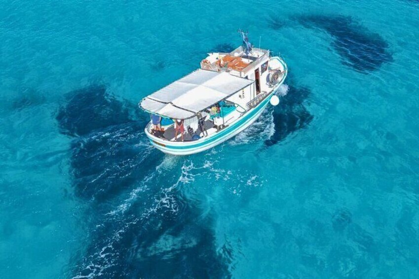 A boat with a covered deck and passengers, floating on clear blue water. 3