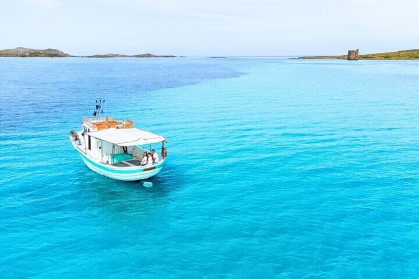 A boat on turquoise water with a rocky island in the distance. 1