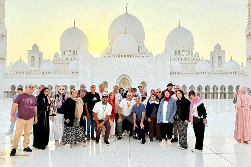Un groupe de personnes posant devant une structure architecturale blanche dotée de coupoles. 1