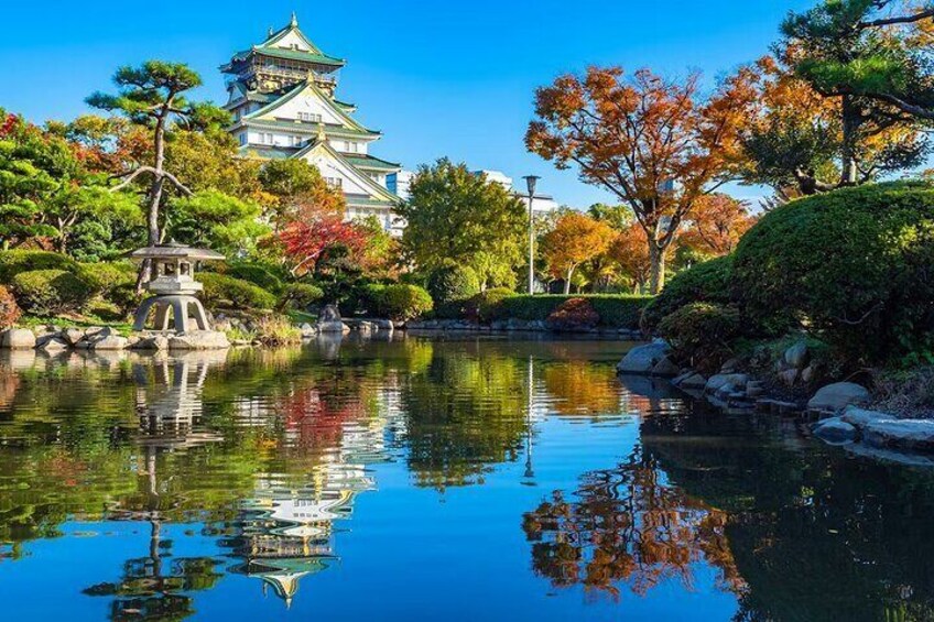 A traditional Japanese building with a multi-tiered roof, surrounded by autumn foliage and a calm pond reflecting the structure. 5