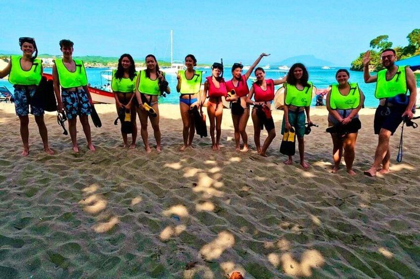 A group of people on a beach with life vests, some holding snorkeling gear. 5