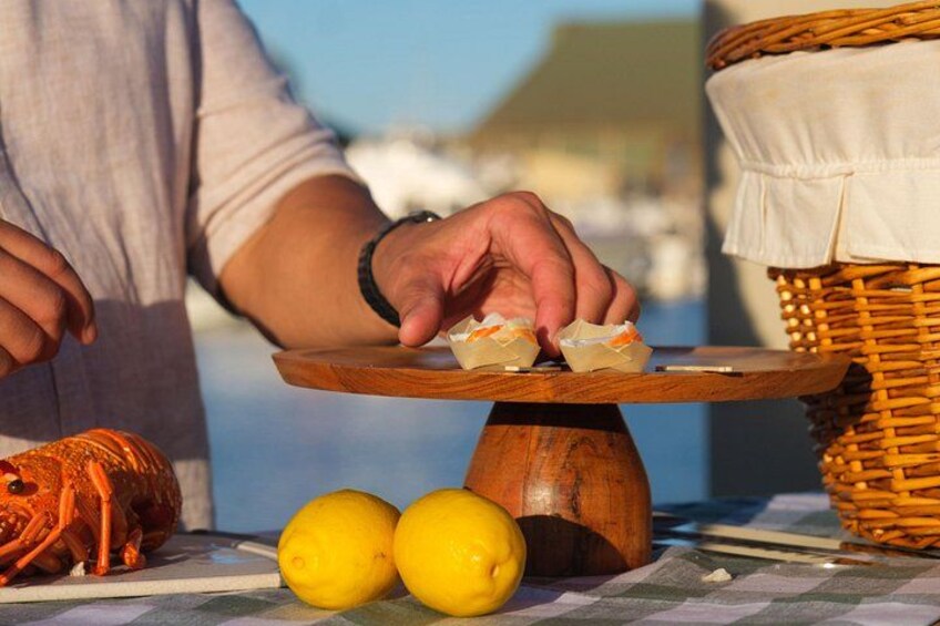 Una persona appoggia un pasticcino su un tavolo di legno con limoni e un aragosta. 3