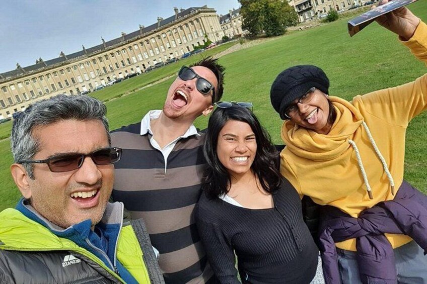 Eine Gruppe von Personen macht ein Selfie vor einem großen, historischen Gebäude mit einer grünen Rasenfläche. 3