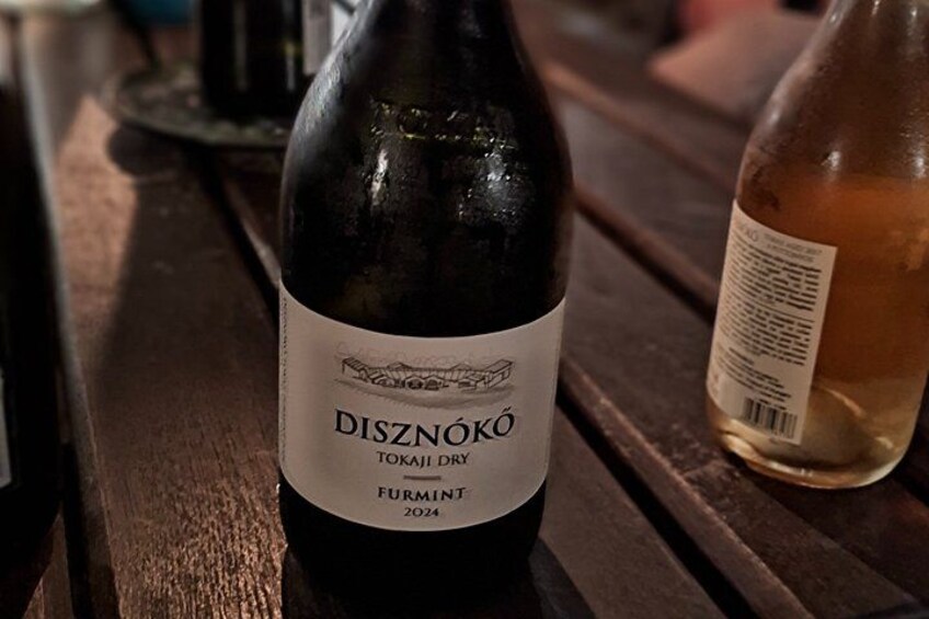 A bottle of DISZNÓKÓ Tokaj DOC 2024 wine on a wooden table. 4