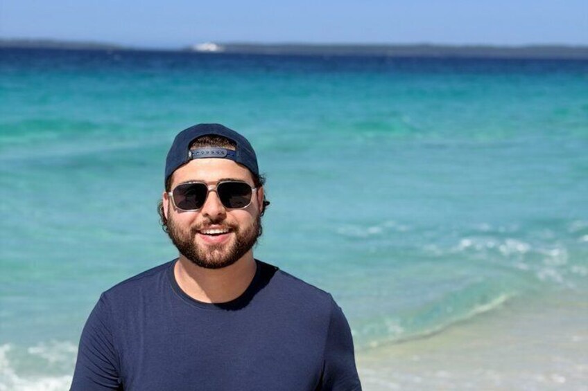 A person standing on a beach with a clear blue sky and ocean in the background. 4
