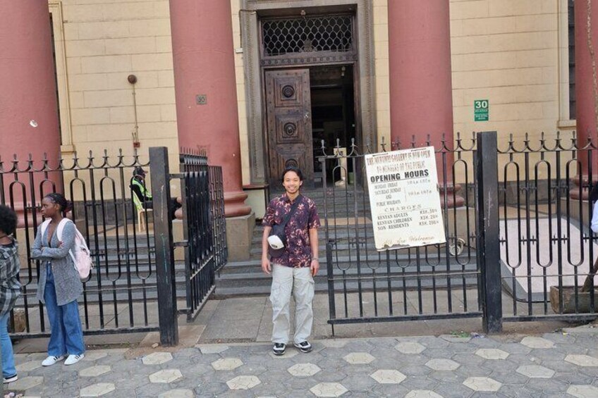 A building entrance with a signboard, a metal gate, and a person standing in front. 2