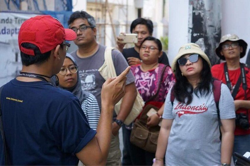 A group of people standing outdoors, some wearing hats and carrying bags. 5