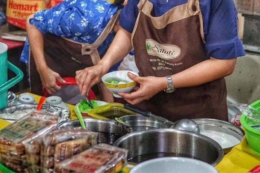 A street food vendor preparing food, with various cooking utensils and ingredients visible. 2