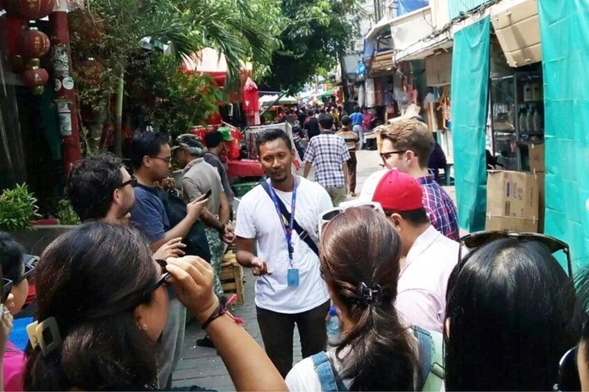 A crowded outdoor market with people shopping and interacting. 1