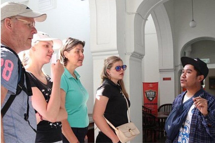 A group of people standing in an indoor area with white columns and a red banner in the background. 4