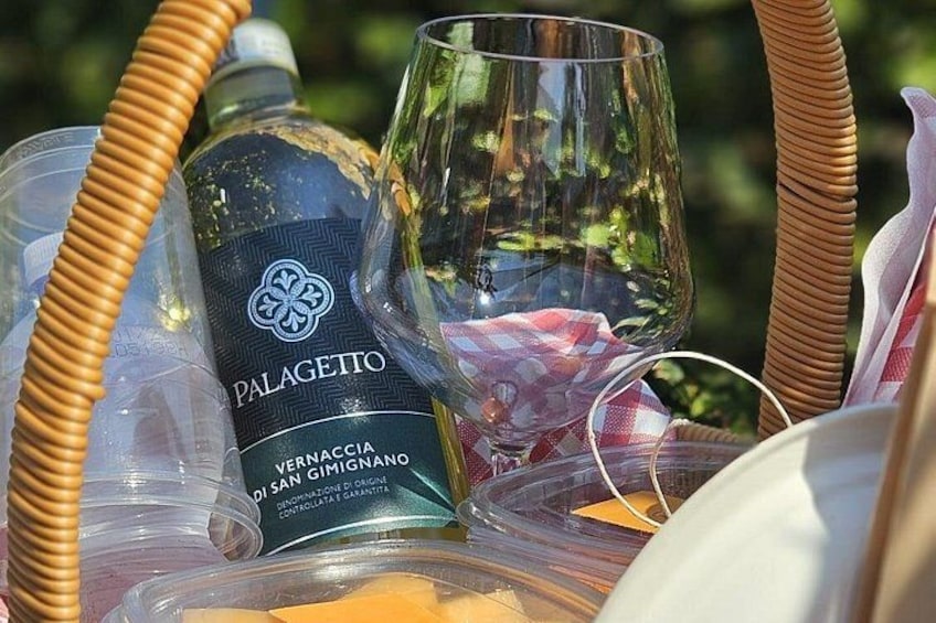 A wicker basket containing a bottle of Palagetto wine, a glass, and a checkered napkin. 2