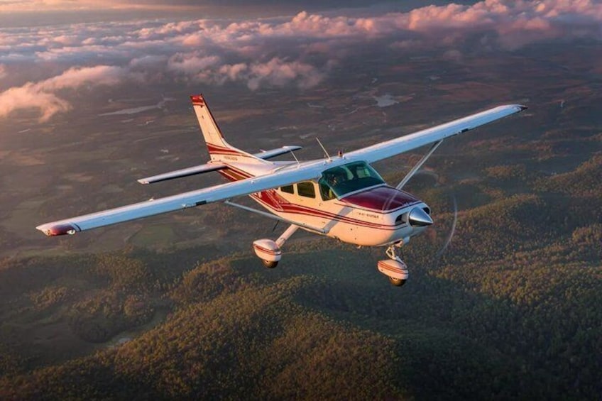 Un pequeño avión volando sobre un paisaje boscoso. 4