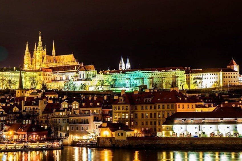 A nighttime cityscape with illuminated historic buildings and a river. 4