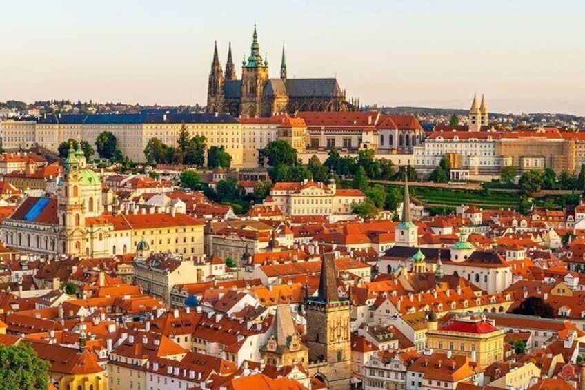 A cityscape with historic buildings, a prominent church with a tall spire, and a large castle-like structure in the background. 5