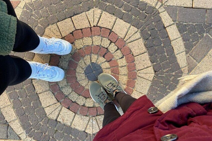 A circular brick pattern on the ground with a person's feet in the center. 4