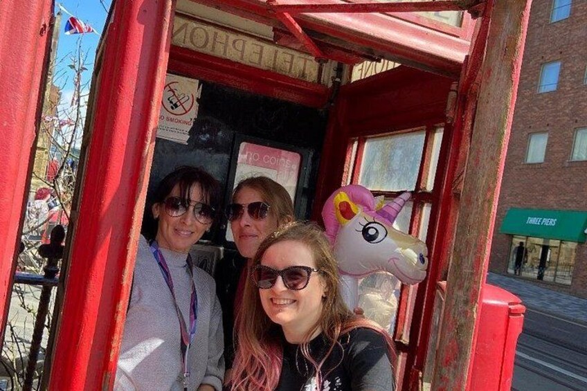 A red telephone booth with a unicorn decoration and a sign that reads 'THREE PIES.' 2
